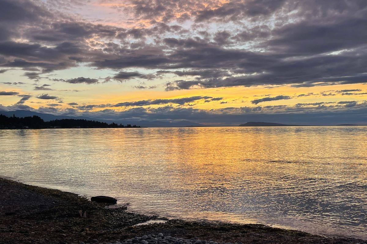 Sunset over the water from a pebble beach on the Vancouver Island coast