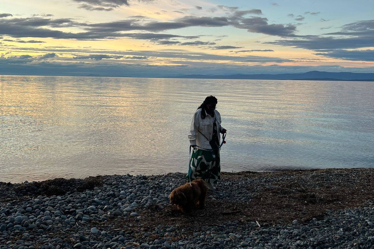 A woman and her dog on a pebble beach at sunset on Vancouver Island